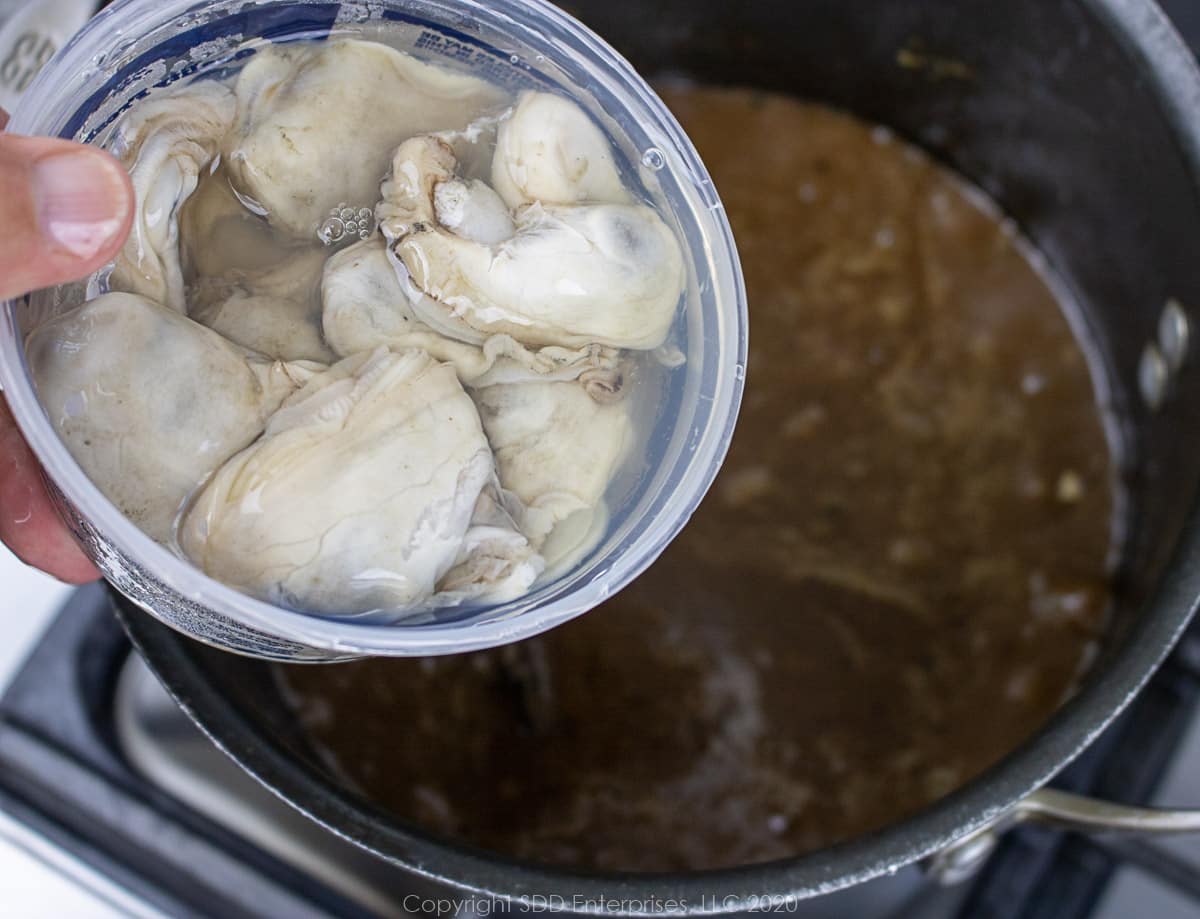 oysters being added to seafood gumbo in a stockpot