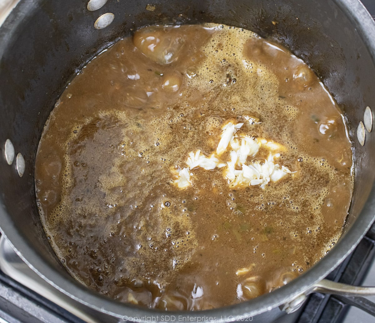 crabmeat added to seafood gumbo in a stockpot