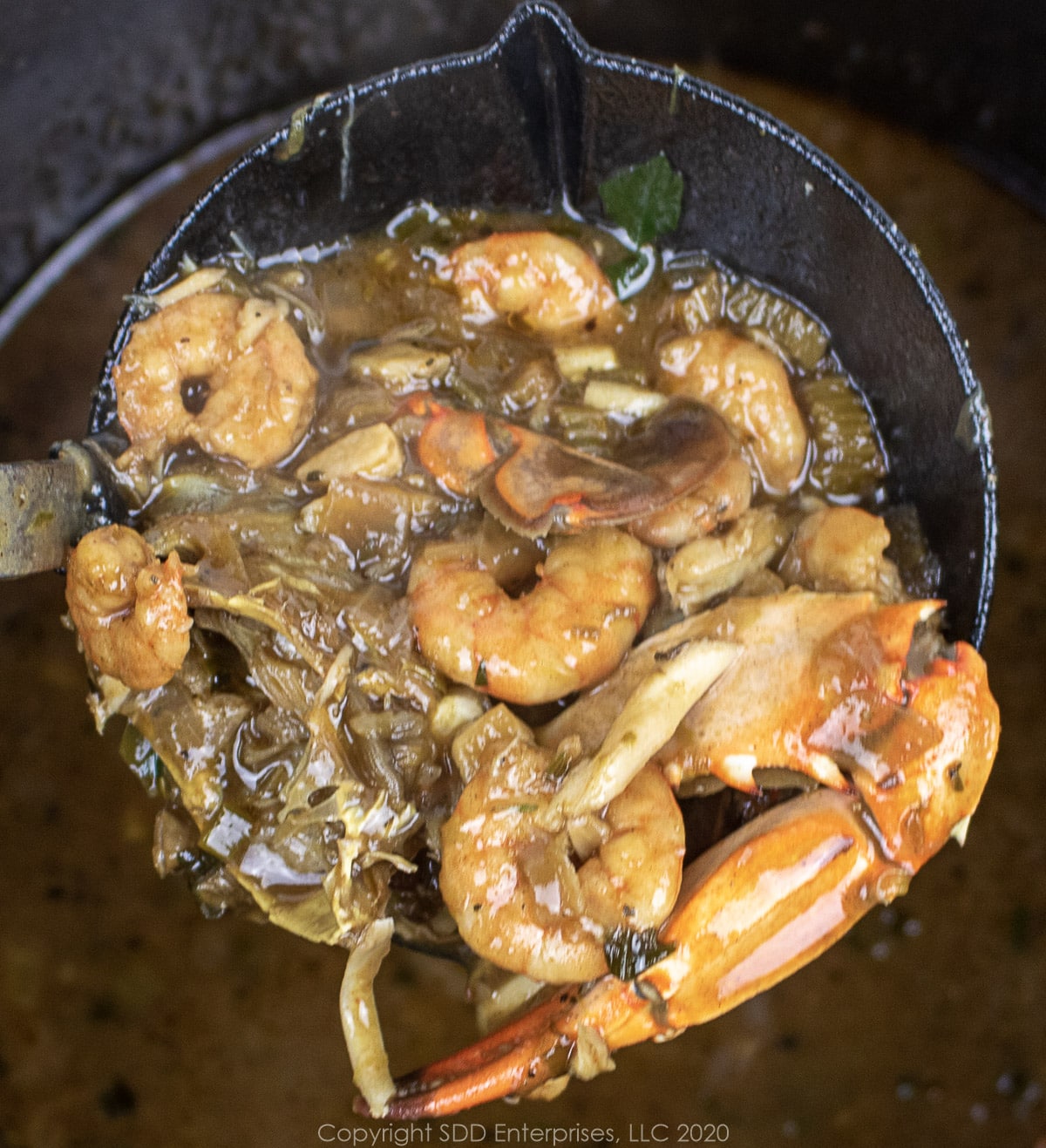 a ladle of seafood gumbo over stockpot