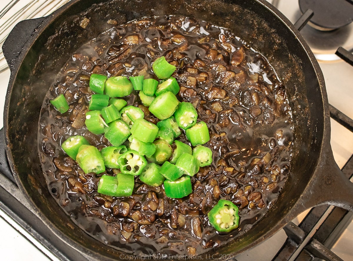 cut okra added to a roux mixture in a cast iron Dutch oven