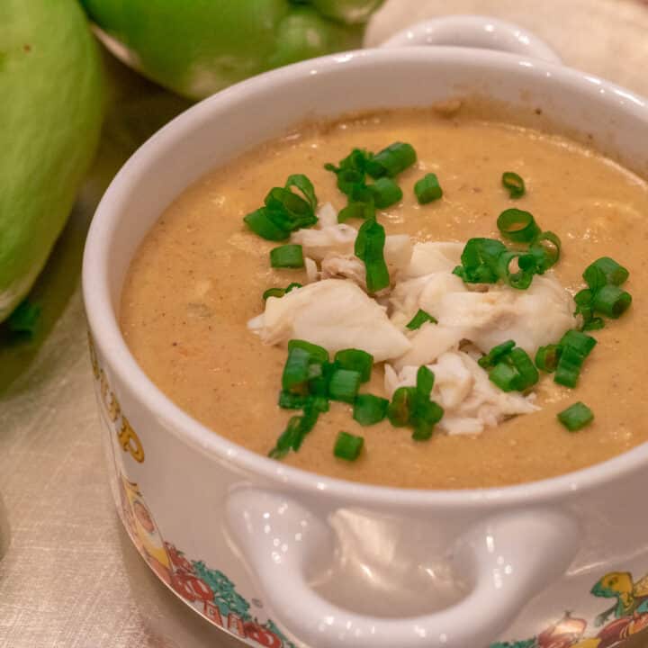 Mirliton crab bisque in a bowl with crabmeat and green onion garnish and whole mirlitons