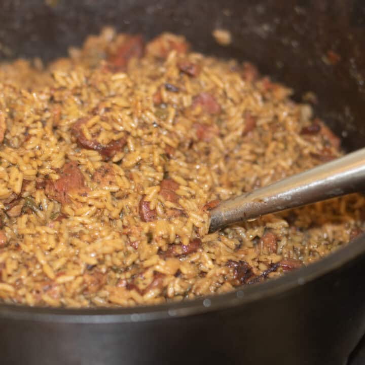 cajun jambalaya with sausage in a large cast iron pot with a serving ladle