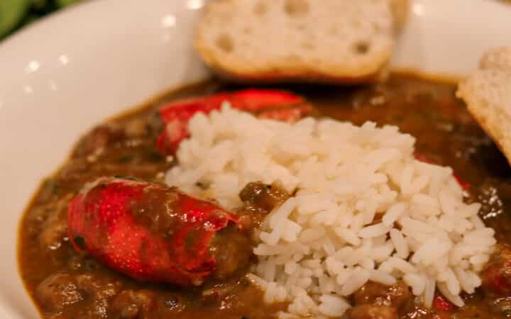 crawfish bisque with stuffed heads and rice in a white bowl with french bread and salad