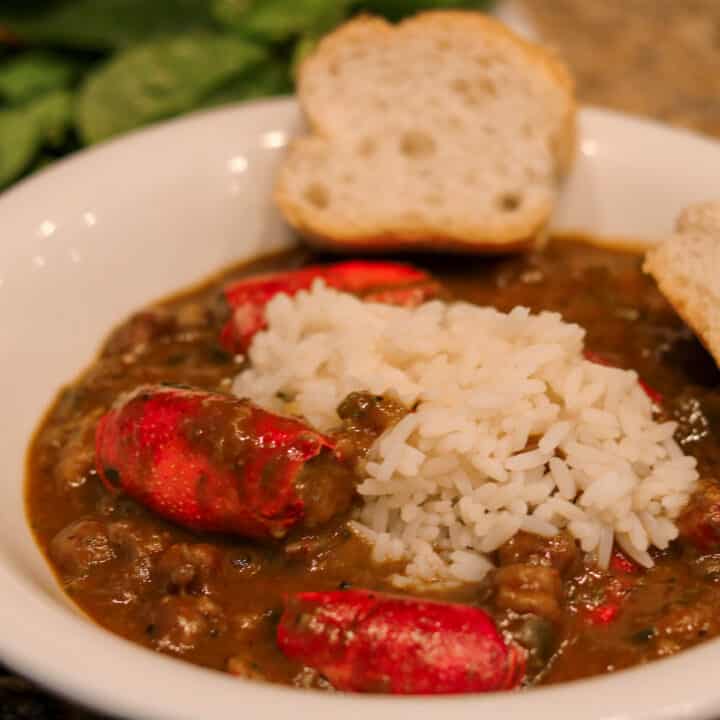 crawfish bisque with stuffed heads and rice in a white bowl with french bread and salad