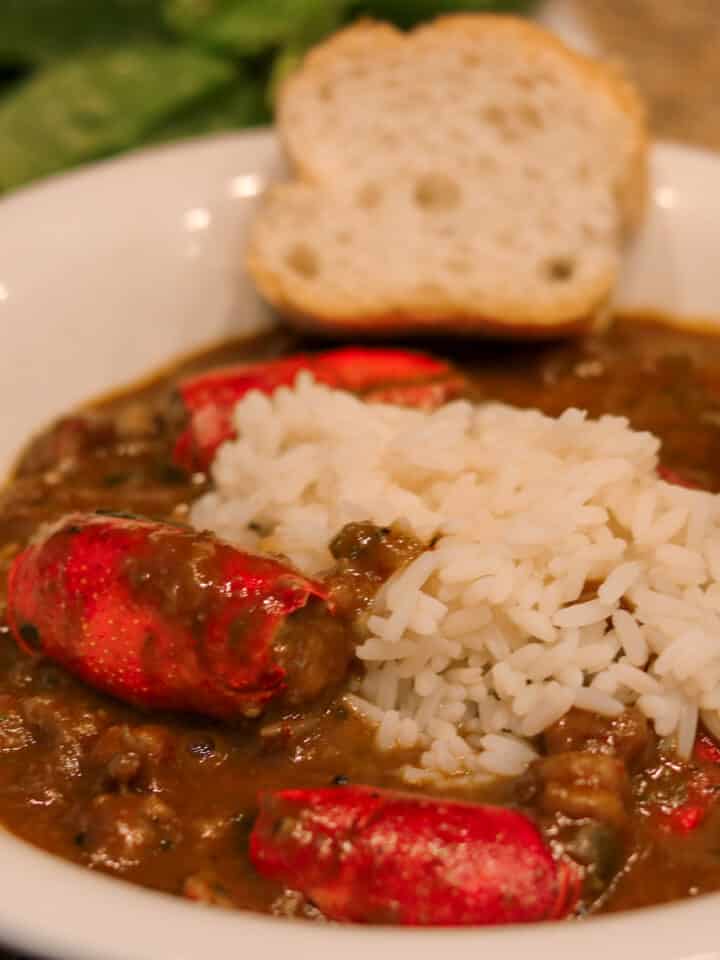 crawfish bisque with stuffed heads and rice in a white bowl with french bread and salad