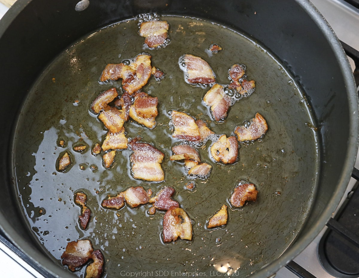 bacon pieces frying in a dutch oven