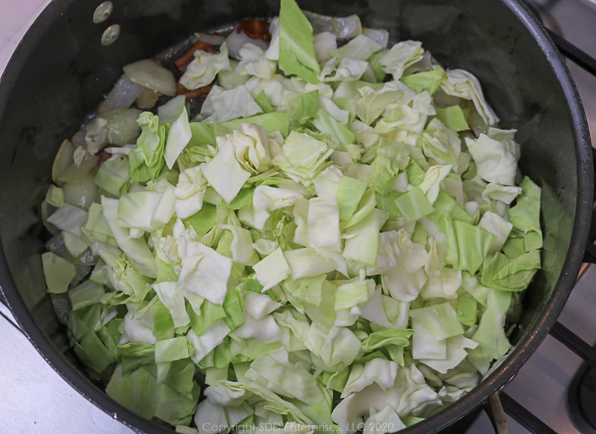 chopped cabbage with bacon and onions in a dutch oven