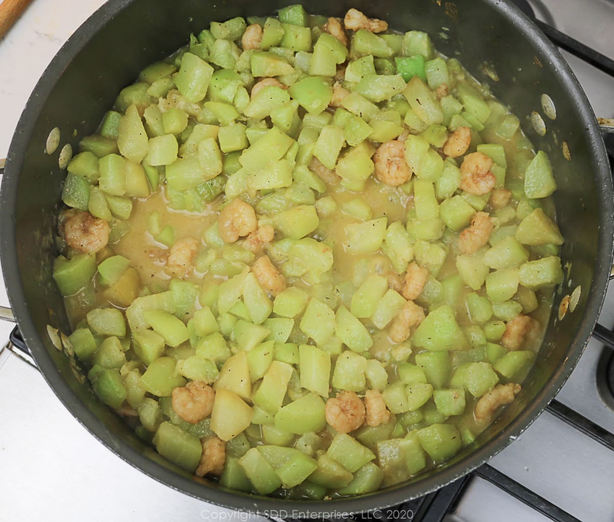 chopped mirliton simmering in a Dutch oven