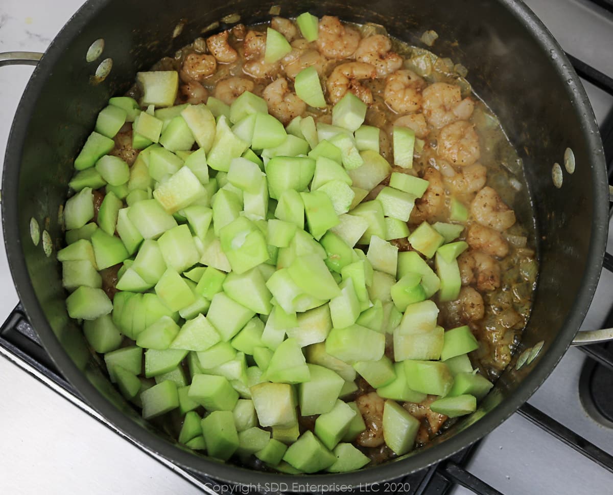 chopped mirlitons added to shrimp in a Dutch oven