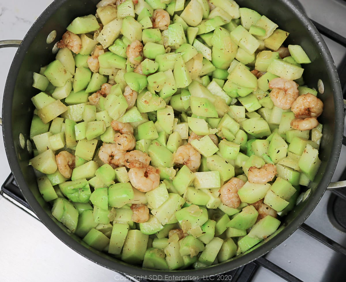 chopped mirliton and shrimp simmering in a Dutch oven