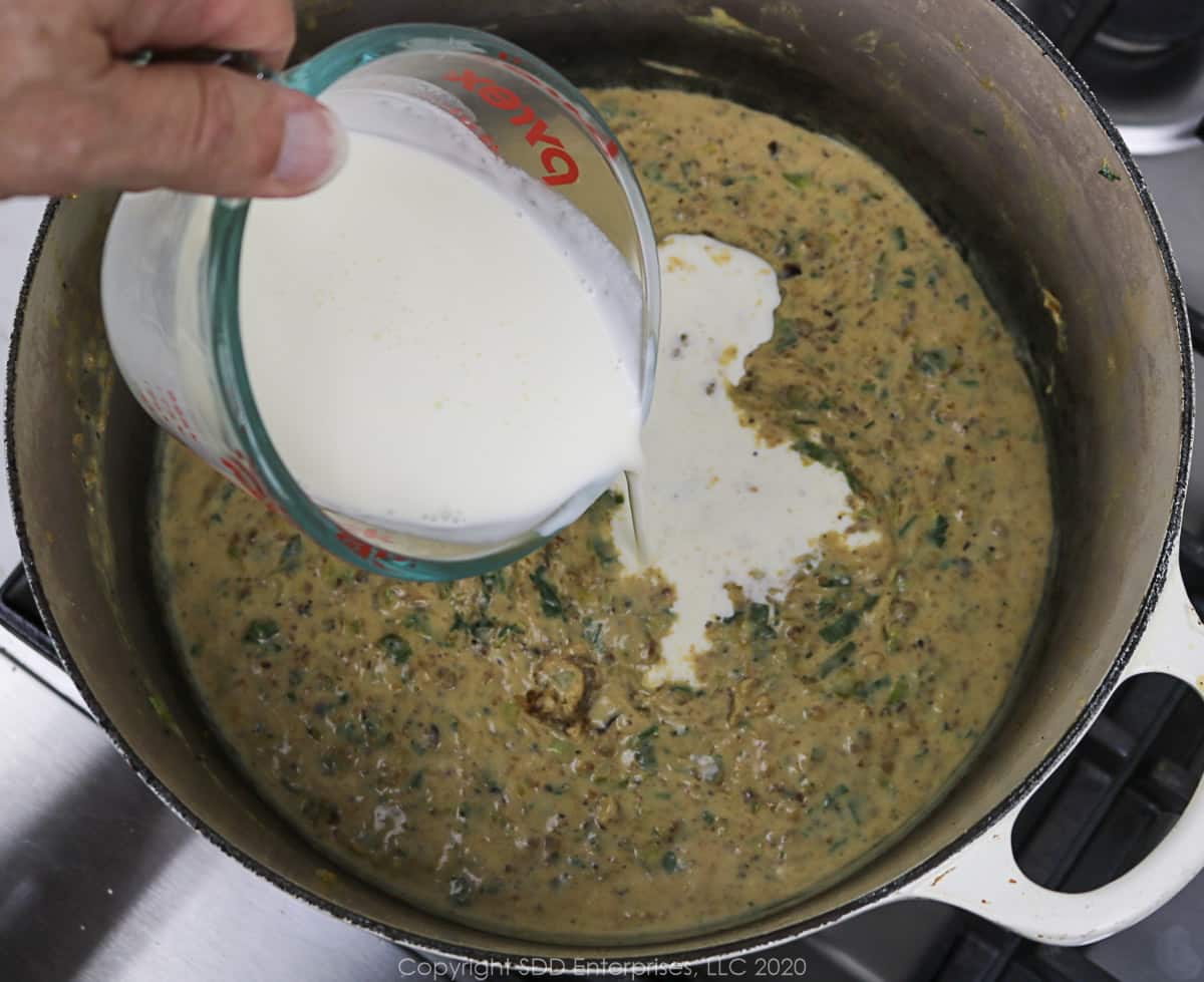 heavy cream being added to roux mixture in a dutch oven