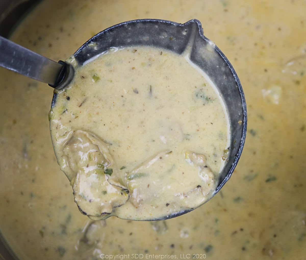 a ladle of oyster soup over a dutch oven