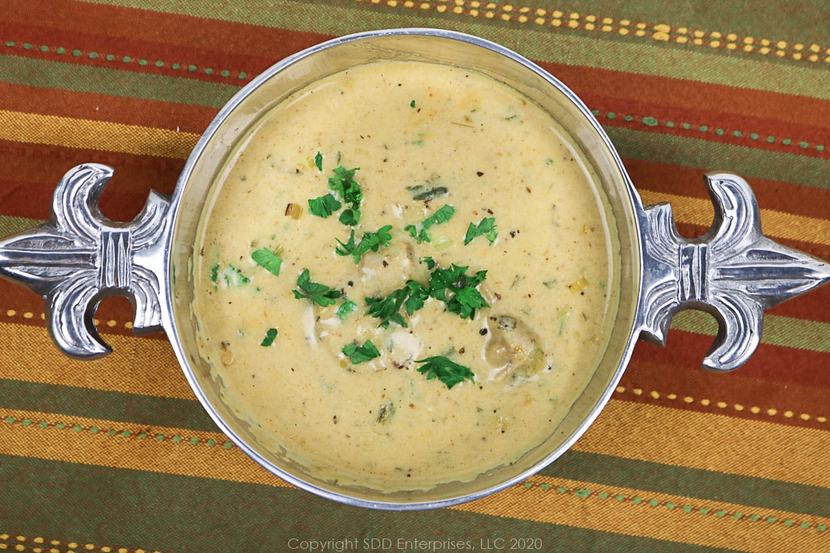 oyster soup in a silver bowl with parsley flakes