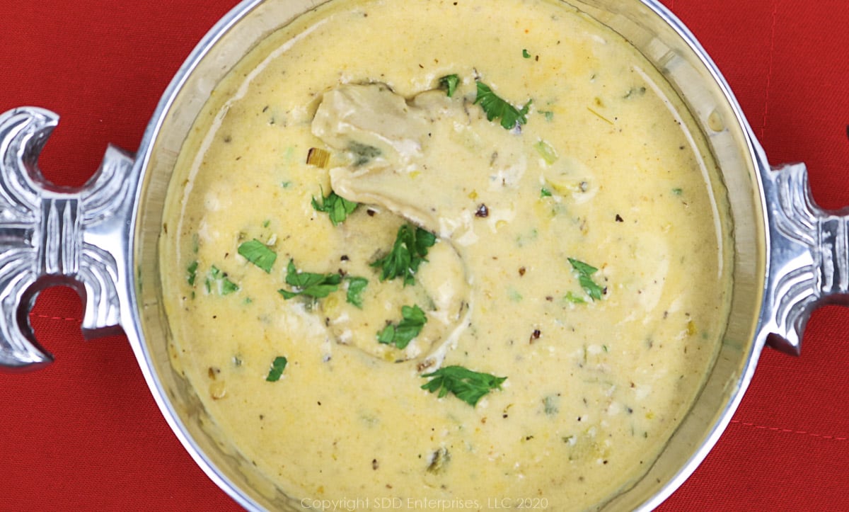 oyster soup in a silver bowl with parsley flakes