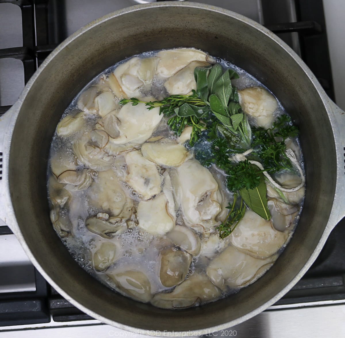 oysters with fresh herbs simmering in oyster liquor