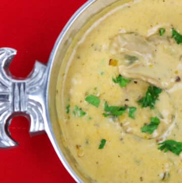 oyster soup in a silver bowl with fleur de lis on a red background