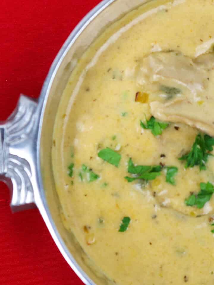 oyster soup in a silver bowl with fleur de lis on a red background