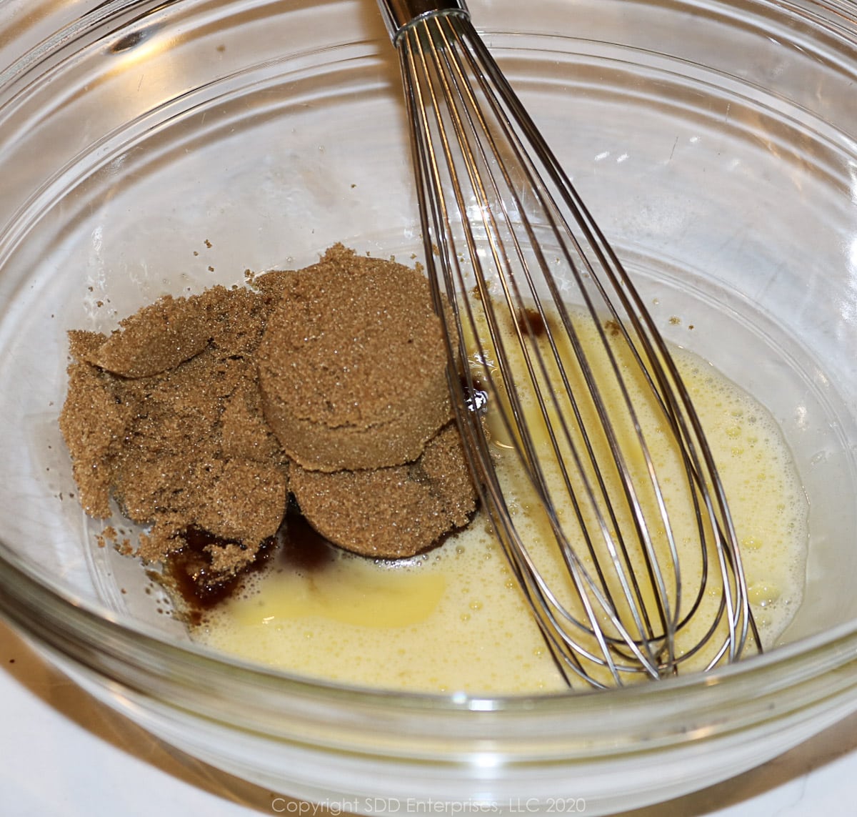 dark brown sugar added to egg in a glass bowl