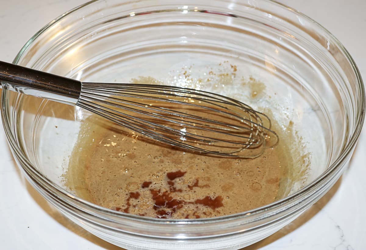 vanilla extract added to brown sugar and egg mixture in a glass bowl