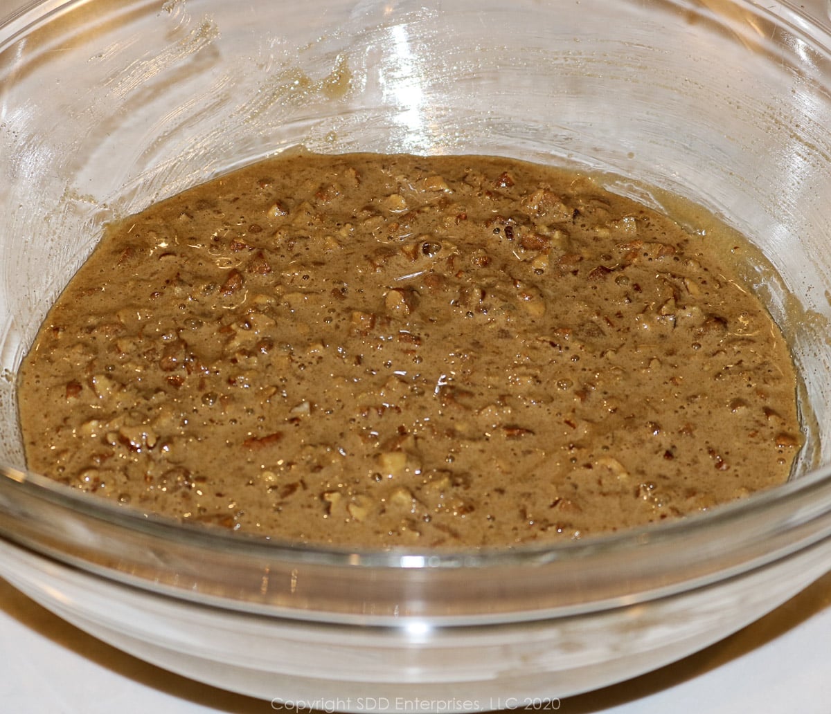 chopped pecans with brown sugar egg mixture in a glass bowl