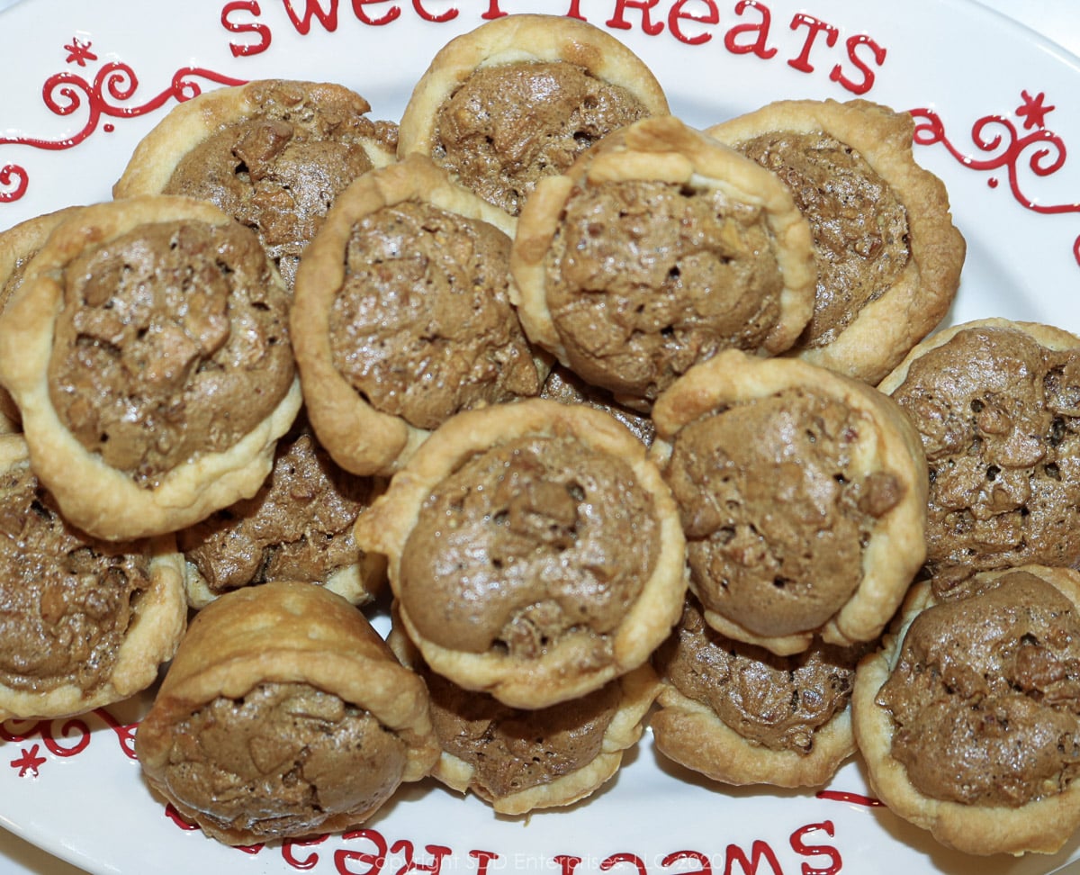 several pecan tarts on a white holiday dish