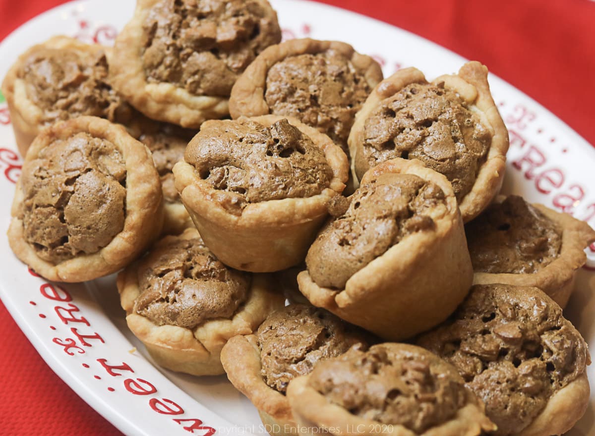 several pecan tarts on a white holiday dish