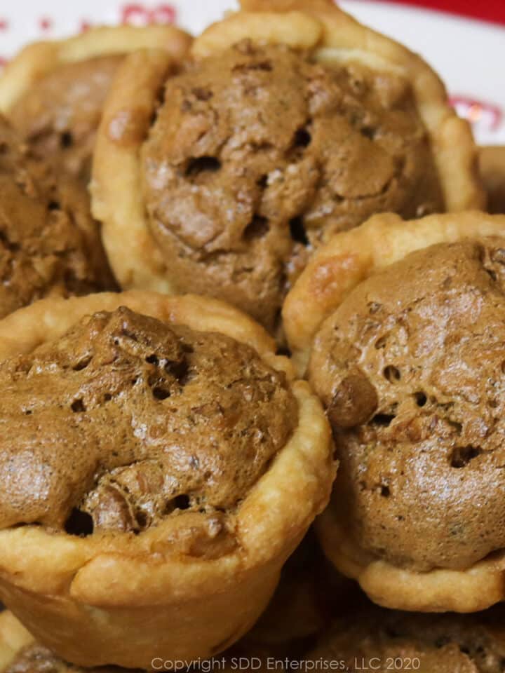 several pecan tarts on a white holiday dish