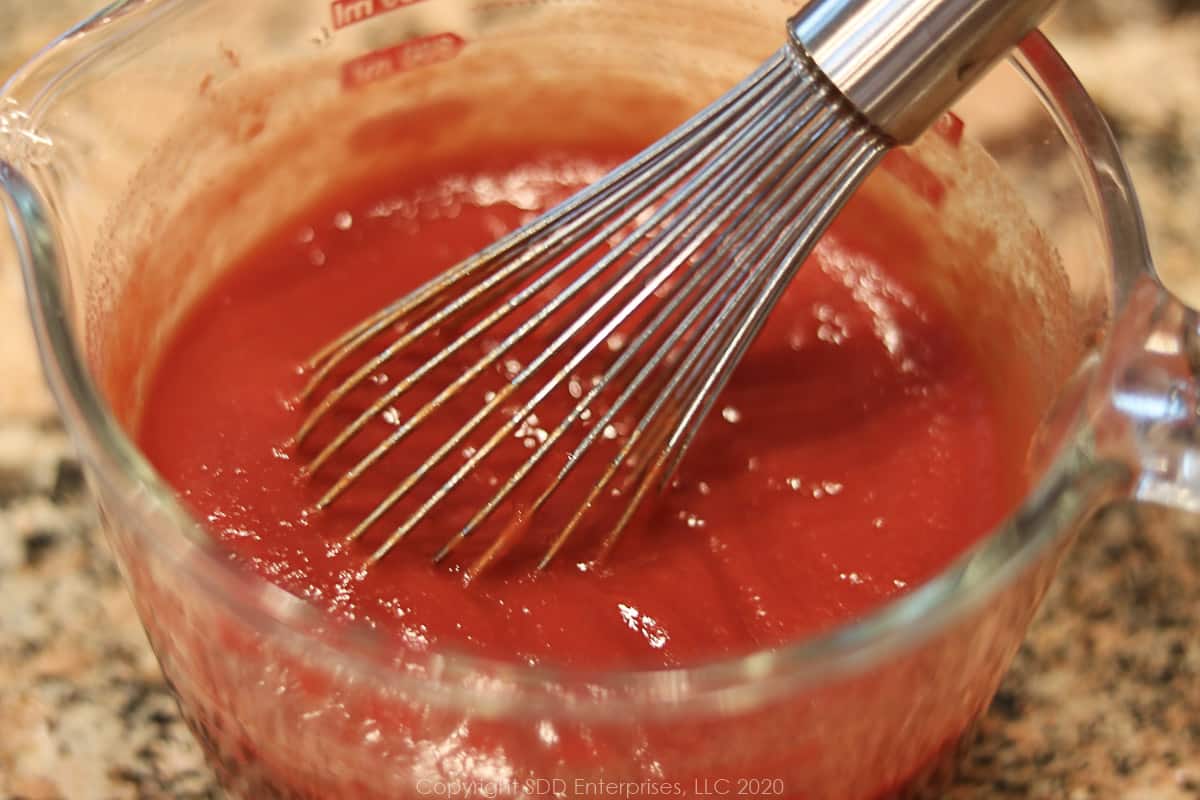 red sauce for meatloaf in a measuring cup with a whisk