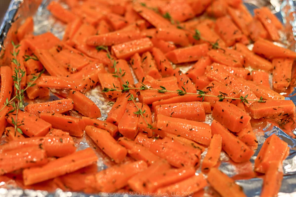 carrots with butter, dry thyme and fresh thyme on a baking sheet