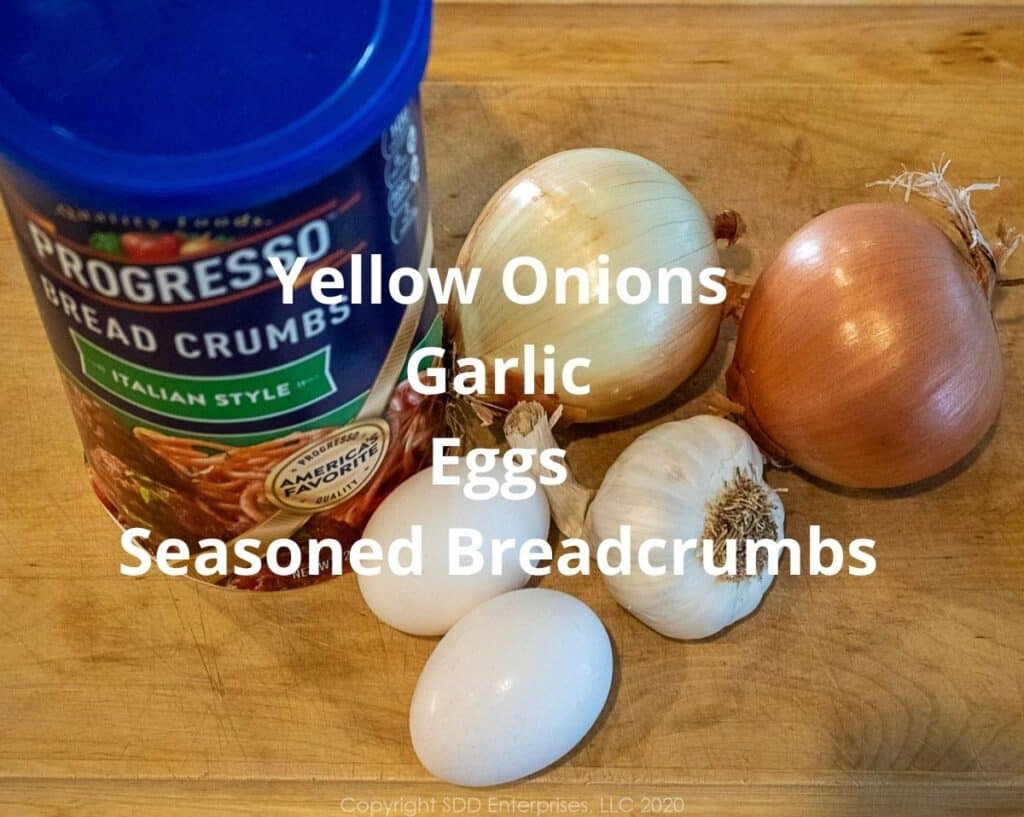yellow onions, garlic, eggs and seasoned breadcrumbs o a cutting board