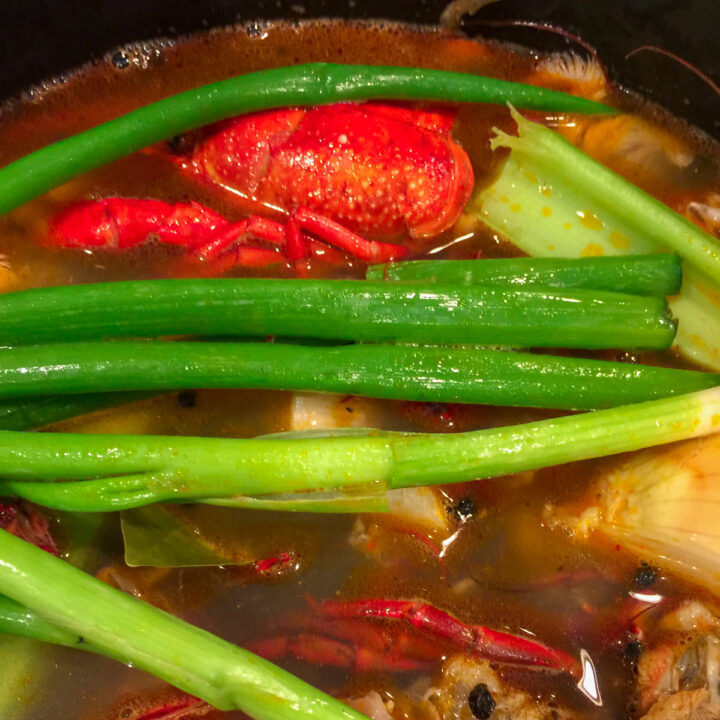 crawfish shells, green onions, yellow onions and celery with water in a stock pot