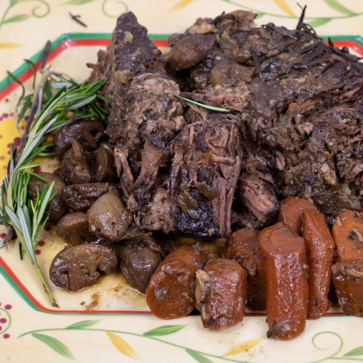 pot roast with carrots, mushroom and rosemary on a serving platter