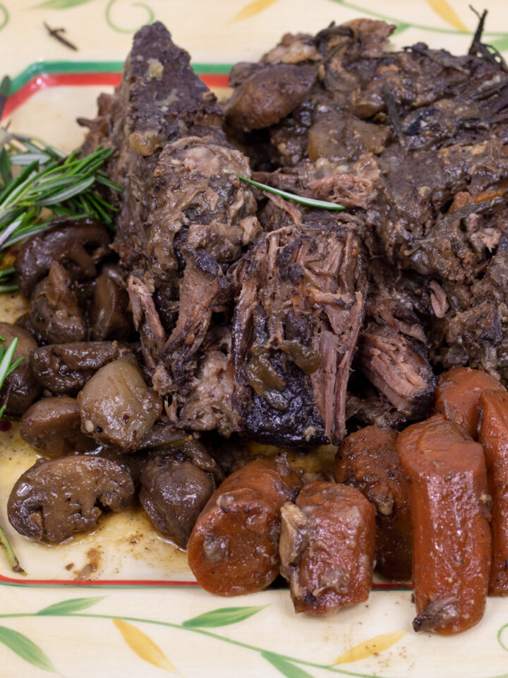 pot roast with carrots, mushroom and rosemary on a serving platter