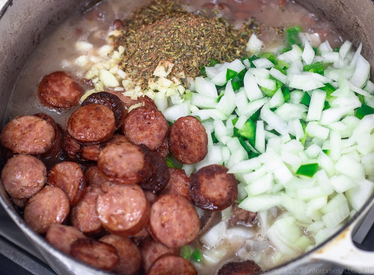 fried sausage, vegetables and spices in a Dutch oven of red beans