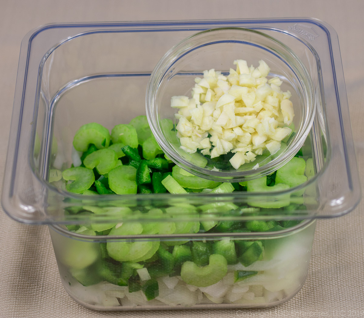 chopped yellow onions, bell peppers, celery and garlic in prep bowls