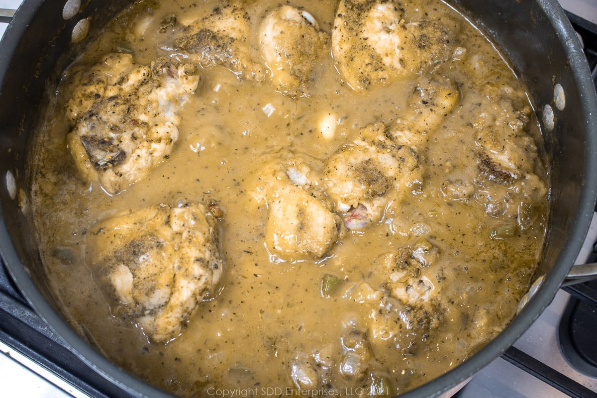 chicken simmering in gravy in a Dutch oven