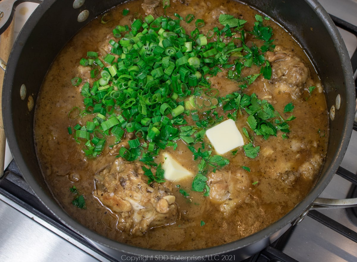 green onions, parsley and butter added to smothered chicken in a Dutch oven