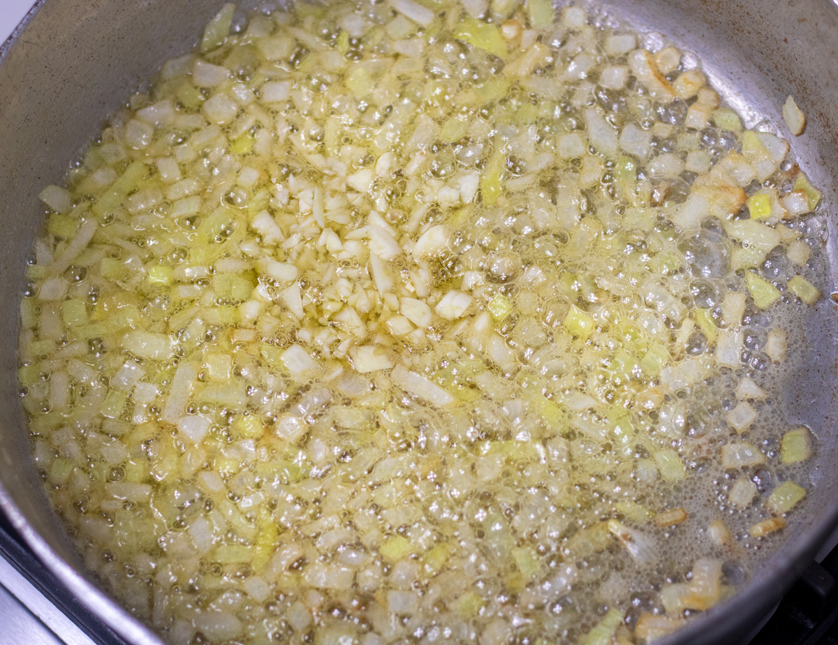 garlic and yellow onions sauteing in utter in a large sauce pan
