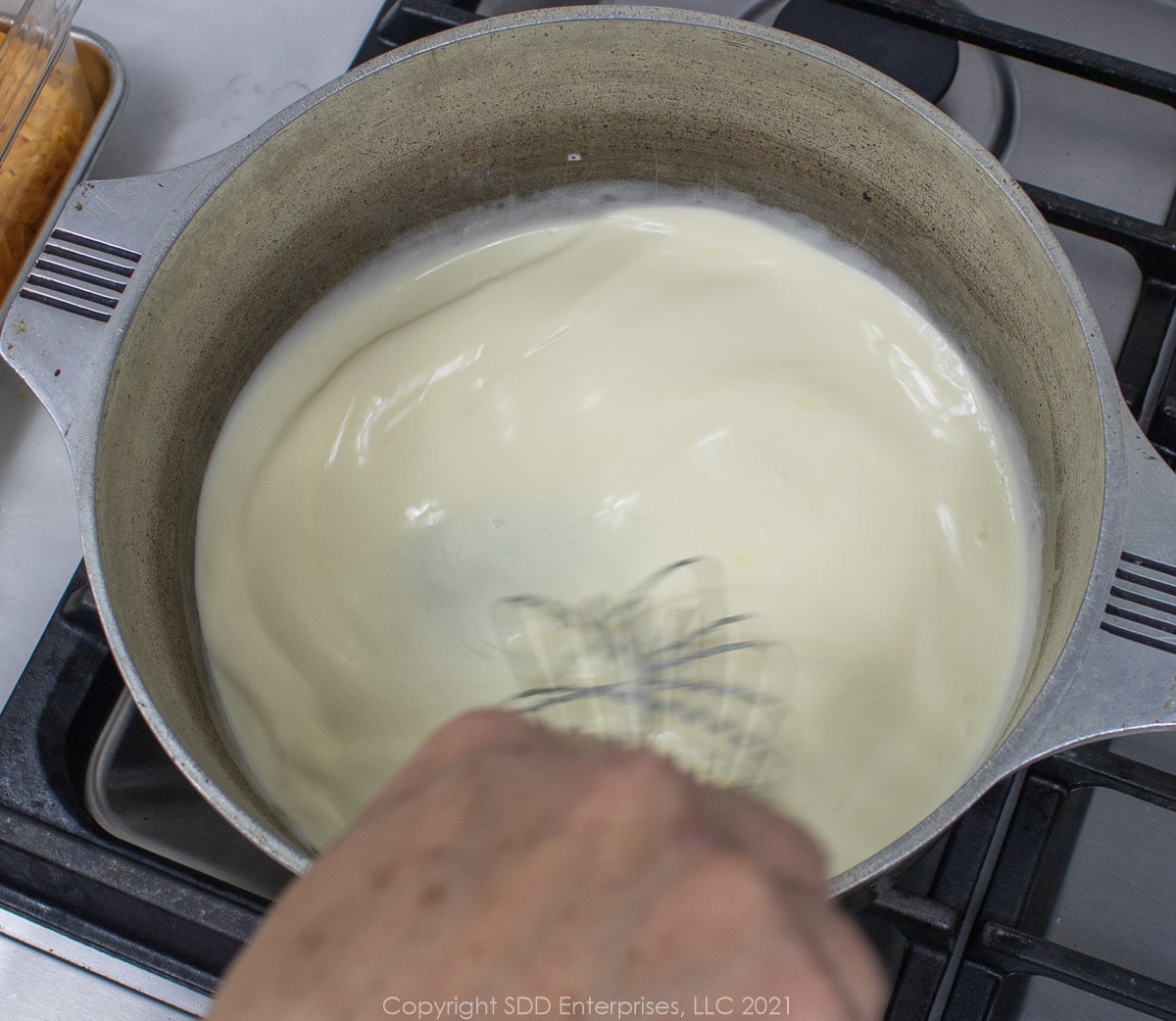 heavy cream, eggs and butter being whisked in a Dutch oven