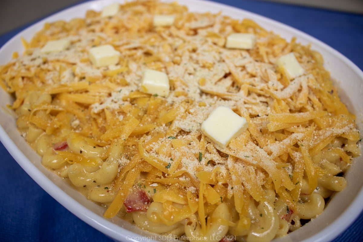 crawfish mac and cheese topped with breadcrumbs and butter in a prepared casserole dish ready for the oven