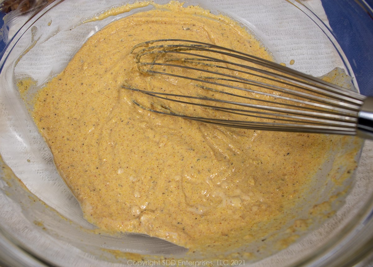 whisking wet and dry ingredients in a glass bowl for fritters