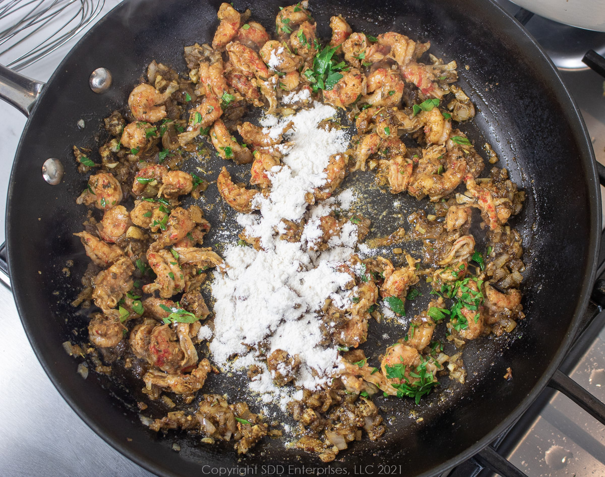 crawfish tails and AP flour added to sautéing onions and aromatics in a frying pan