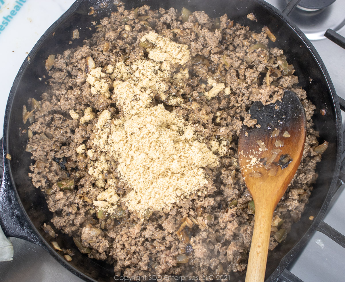 Brown sugar, dry mustard and spices added to browned ground beef in a frying pan