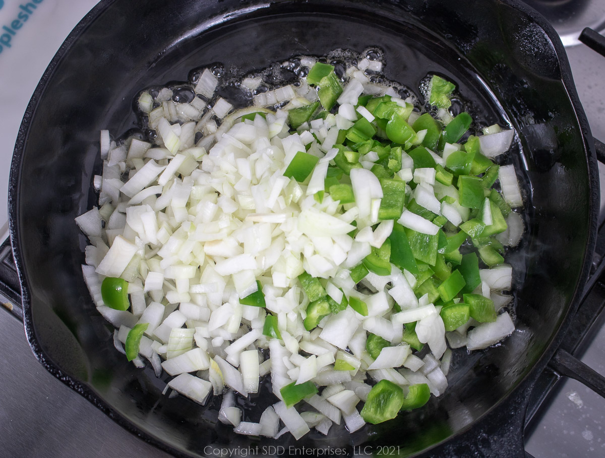 Yellow onions and green peppers ina cast iron frying pan