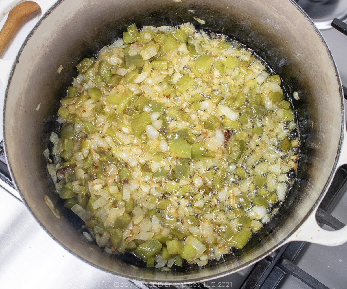 yellow onions and bell peppers fring in bacon grease in a Dutch oven