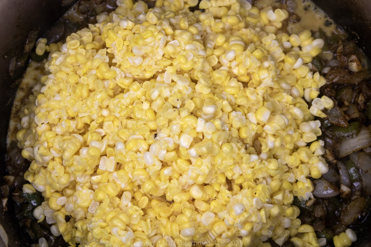 fresh corn with frying vegetables in a Dutch oven