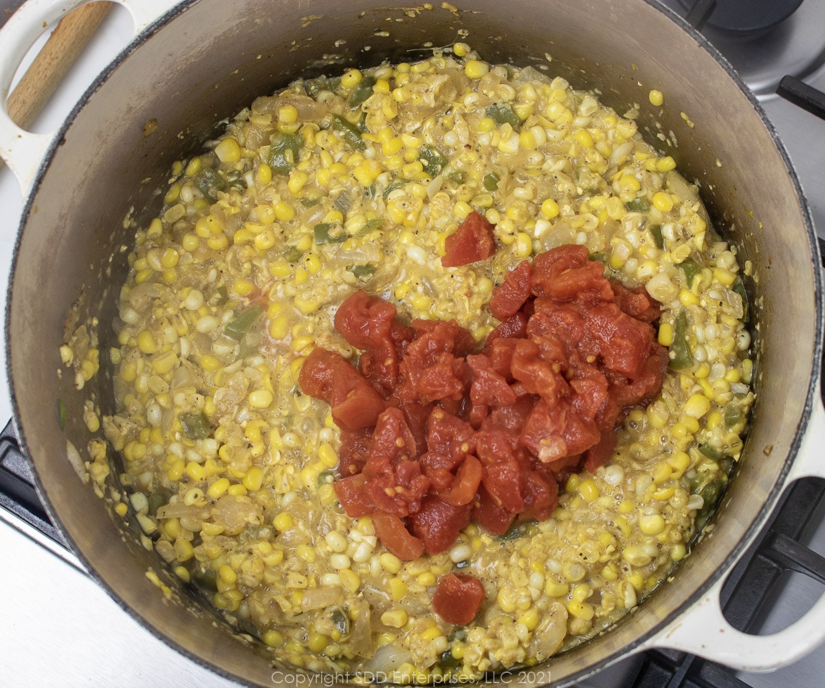 chopped tomatoes added to corn in a Dutch oven