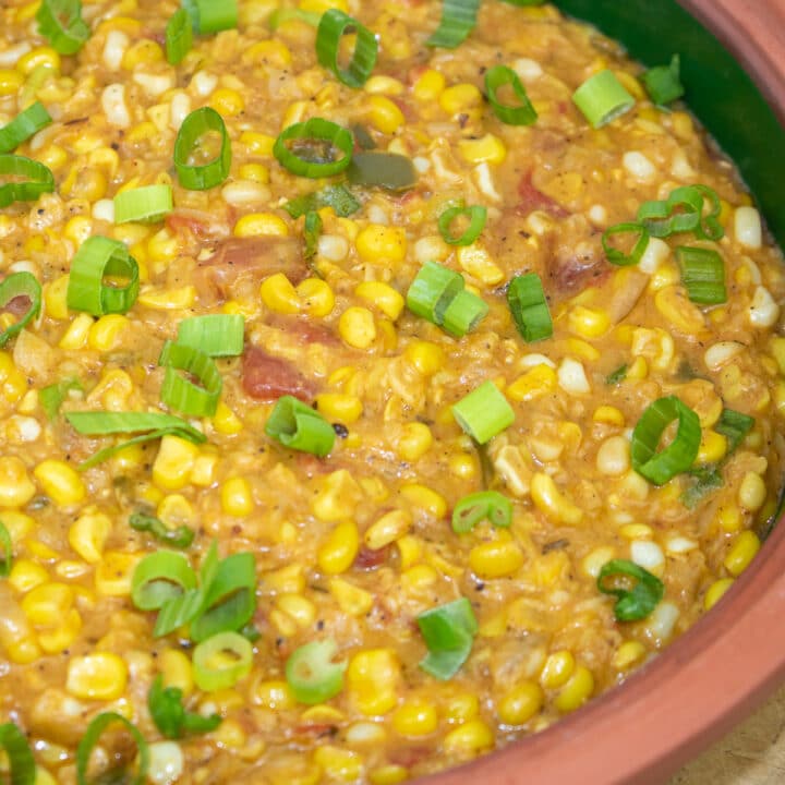 corn maque choux with green onion garnish in a brown bowl