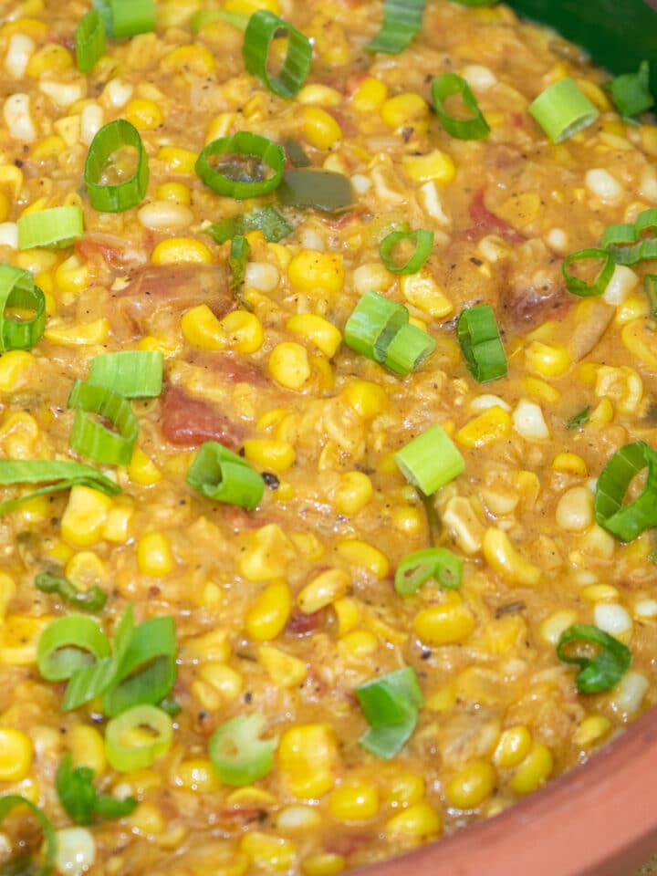 corn maque choux with green onion garnish in a brown bowl