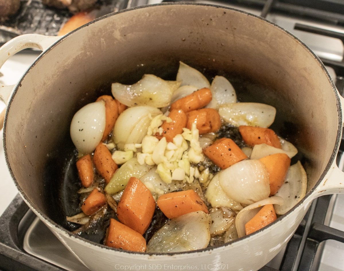 garlic added to onions and carrots in a Dutch oven